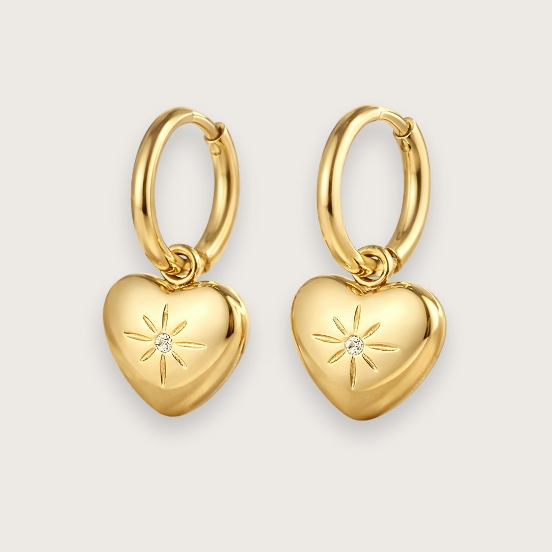 Guldbelagte hoops med smukt hjertevedhæng.
De fine hjertevedhæng har smuk lille zirkon i midten, der giver hoop-øreringene et eksklusivt og elegant udtryk.
Øreringene er fremstillet i 14k guldbelagt rustfrit stål med PVD-coating, hvilket gør dem både vandfaste og slidstærke.
De fine hjerteøreringe er en sød og kærlig gave til din mor, kæreste, veninde - eller til dig selv!
Perfekte som valentinsgave, konfirmationsgave, studentergave eller bare-fordi-gave til en, du holder af.
Mål: Øreringen