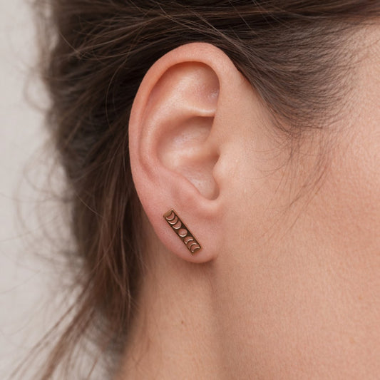 Smukke ørestikkere i 18k forgyldt stål.
De elegante Luna stav-ørestikkere med månefaser kombinerer et stilrent, geometrisk design med et dekorativt himmelmotiv. Den slanke, rektangulære form giver øreringene et moderne udtryk, mens de udskårne månefaser tilfører en fin detalje, der fanger lyset og giver smykket karakter.
Designet fungerer både minimalistisk og symbolsk. Månefasemotivet har længe været forbundet med naturens rytme og forandring. Månesmykker. Måneøreringe.