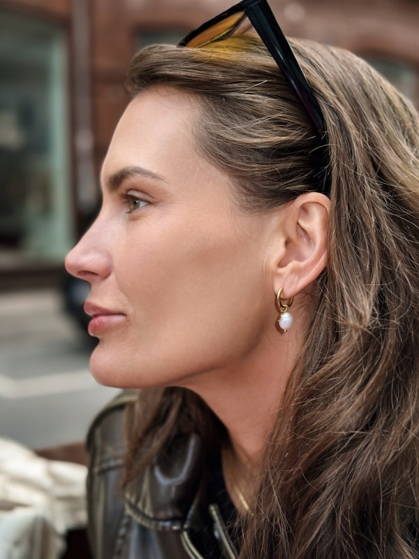 Elsie Øreringe – 18k forgyldt stål med ferskvandsperle og stjernevedhæng

Små elegante hoop-øreringe med ferskvandsperler og fine stjernevedhæng.

De elegante hoops i 18k forgyldt rustfrit stål kombinerer den klassiske ferskvandsperle med en lille stjernedetalje, der giver øreringene et levende og feminint udtryk.

Øreringene er lette og behagelige at bære og passer smukt til både opsat og løsthængende hår.

PVD-forgyldningen er vandfast og slidstærk.
guldhoops med ferskvandsperler
