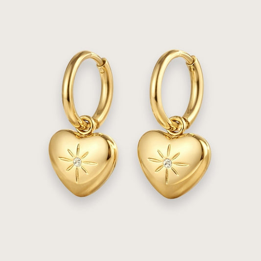 Guldbelagte hoops med smukt hjertevedhæng.

De fine hjertevedhæng har smuk lille zirkon i midten, der giver hoop-øreringene et eksklusivt og elegant udtryk.&nbsp;

Øreringene er fremstillet i 14k guldbelagt rustfrit stål med PVD-coating, hvilket gør dem både vandfaste og slidstærke.&nbsp;

De fine hjerteøreringe er en sød og kærlig gave til din mor, kæreste, veninde - eller til dig selv!

Perfekte som valentinsgave, konfirmationsgave, studentergave eller bare-fordi-gave til en, du holder af.

Mål: Øreringen