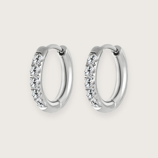 Små sølvfarvede hoops med zirkoner.

De smukke Hallie-hoops er et must-have i enhver smykkesamling.

De små zirkoner giver øreringene et eksklusivt udtryk, og det klassiske design passer til alle lejligheder.&nbsp;

Hallie-øreringene har en diameter på 1 cm, og deres diskrete størrelse gør dem perfekte til hverdag og mix 'n match med andre sølvøreringe.

Hallie-øreringene er fremstillet i sølvtonet rustfrit stål, der er vandfast og slidstærkt.