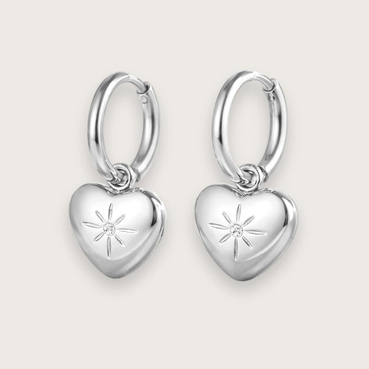 Klassiske sølvfarvede hoops med smukt hjertevedhæng.

De fine hjertevedhæng har smuk lille zirkon i midten, der giver hoop-øreringene et eksklusivt og elegant udtryk.&nbsp;

Øreringene er fremstillet i sølvtonet rustfrit stål med PVD-coating, hvilket gør dem både vandfaste og slidstærke.&nbsp;

De fine hjerteøreringe er en sød og kærlig gave til din mor, kæreste, veninde - eller til dig selv!

Perfekte som valentinsgave, konfirmationsgave, studentergave eller bare-fordi-gave til en, du holder af.