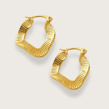 Guldbelagte wavy hoop øreringe. Vandfaste hoop oreringe i rustfrit staal med 18K forgyldning. Ottilie hoop-øreringe fra Chant du Matin. Boelget firkantet design med riflede detaljer og click-down laas. Nikkelfri, blyfri og perfekte som gave.