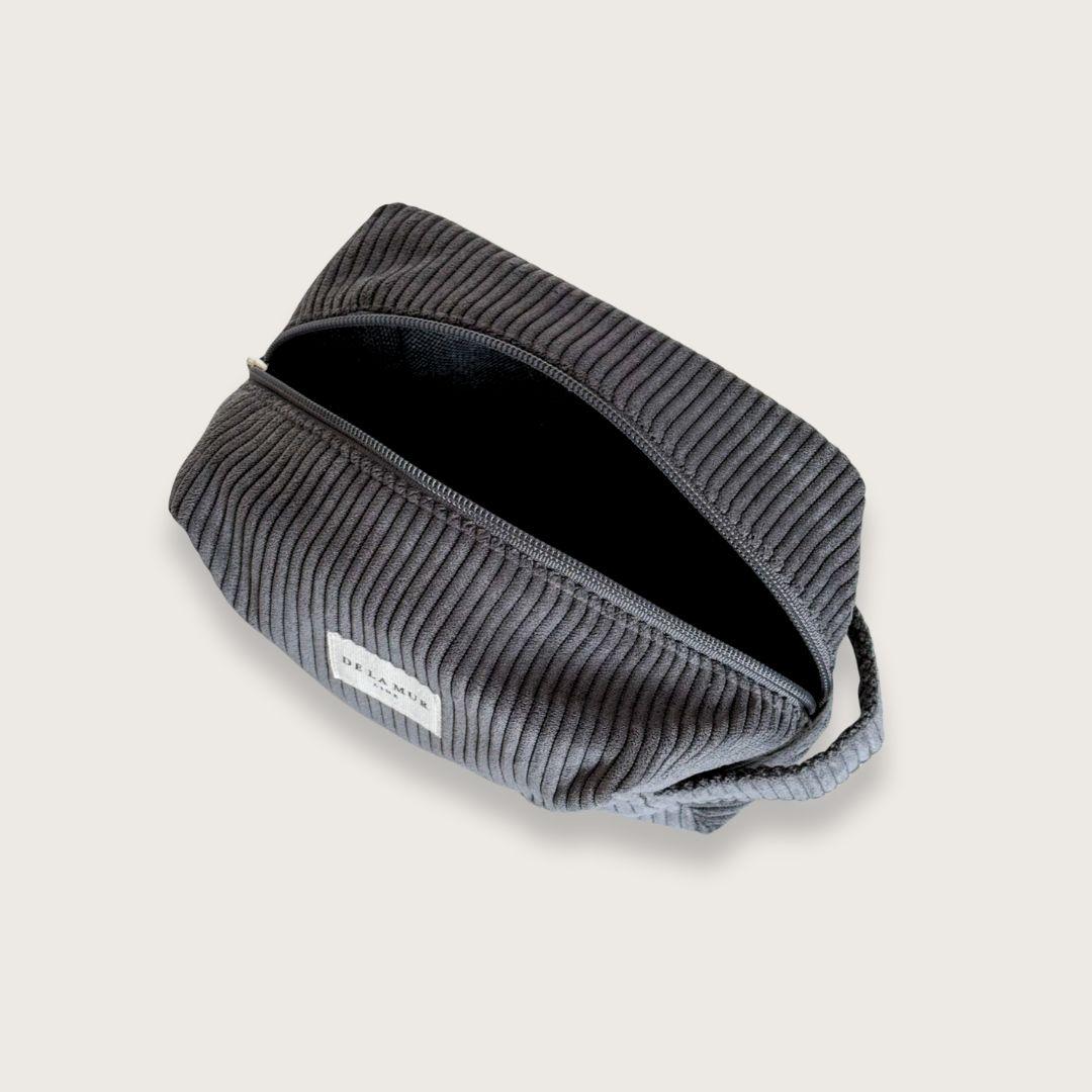 Toilettaske til kvinder. Makeuptaske. Rummelig toilettaske. Lille og rummelig toilettaske i mørkegråt fløjl fra det lille spanske mærke De la Mur.&nbsp;  En blød, rummelig og virkelig pæn lille toilettaske, der rummer meget mere, end man skulle tro.&nbsp;  Toilettasken er syet i tykt og luksuriøst fløjl og har et enkelt, men gennemført udtryk, så du får lyst til at have stående fremme.