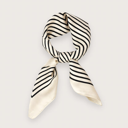 Ory er et smukt og stilrent satintørklæde med sorte striber på en lys, cremefarvet baggrund.&nbsp;

Udtrykket er minimalistisk med et fashion-forward twist på det klassiske silketørklæde og fungerer perfekt som det lille ekstra, der samler outfittet. Et kvadratisk tørklæde i satin, der er nemt at style både casual med jeans og tee – eller mere polished med blazer og solbriller.