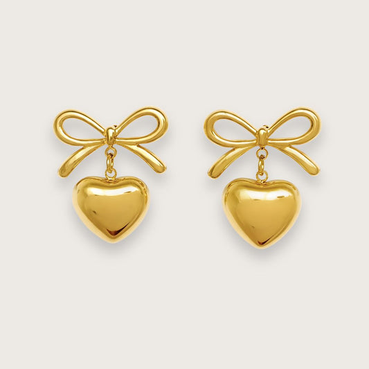 Smukke sløjfeøreringe med hjertevedhæng.&nbsp;

De fine sløjfeøreringe er fremstillet i 18k forgyldt titaniumstål. Under hver sløjfe hænger et fin lille guldhjerte, der bevæger sig yndefuldt med dig. Formen er enkel, feminin og legende. Klassisk og trendy på samme tid.

Carly-øreringene er behagelige at bære og smukke til både opsat og løst hår.

De fine sløjfeøreringe er vandfaste og hverdagsvenlige.

Et par ørestikker, der tilfører et blidt og personligt touch til garderoben.