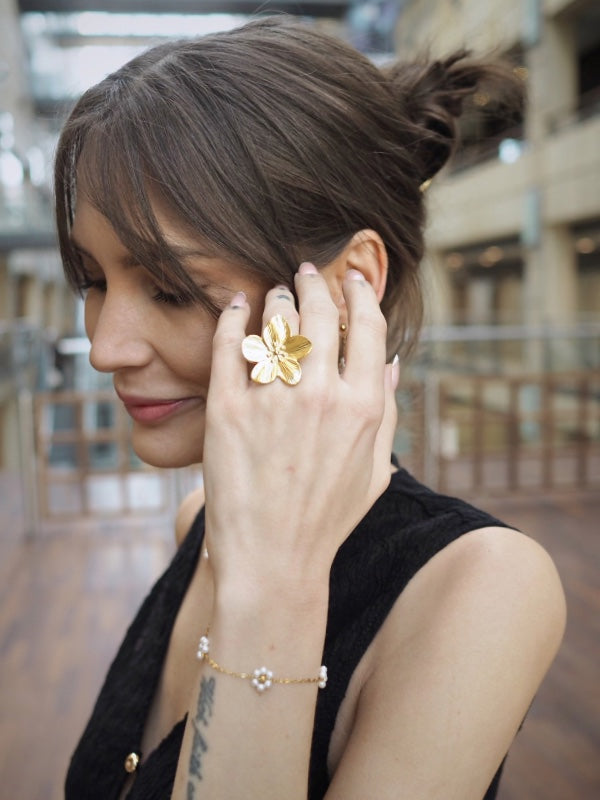 Smuk blomsterring i 18k forgyldt stål

Den smukke Nell guldring er et moderne statement-smykke med en skulpturel blomsterform. Den store blomst giver ringen et markant og eksklusivt udtryk, der kan give et strejf af sommer til ethvert outfit – og enhver dag.

Ringen er fremstillet i rustfrit stål med 18k PVD-forgyldning, som giver en slidstærk guldoverflade og gør smykket mere modstandsdygtigt over for daglig brug.

Kombinationen af rustfrit stål og PVD-belægning gør ringen til et godt valg, hvis du foretræ