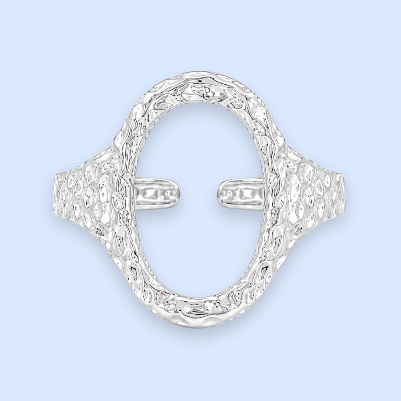 Sølvbelagt oval ring i rustfrit stål med banket overflade

Elvira-ringen er designet med en markant organisk silhuet og en åben oval front, der giver ringen et mere skulpturelt udtryk end klassiske sølvringe. Den hamrede overflade skaber ujævne refleksioner i metallet og giver ringen mere dybde, struktur og karakter fra alle vinkler.

Elvira er en sølvring, der tilfører form, struktur og mere kant til selv en enkel styling.

Ringen er fremstillet i stål med vandfast PVD-sølvbelægning.

oval sølvring 