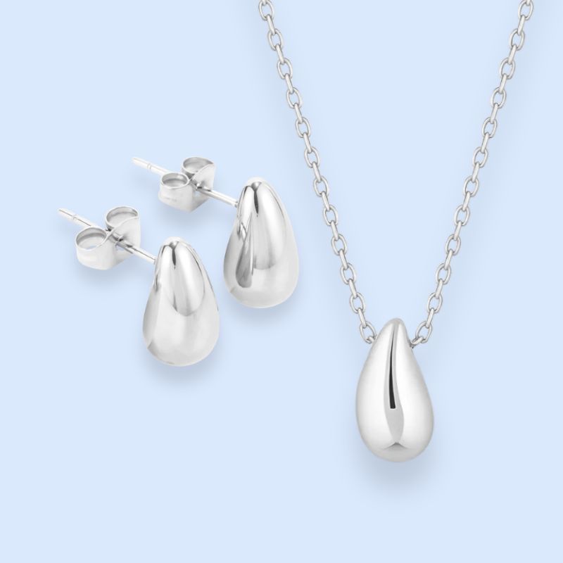 Klassisk smykkesæt i elegant dråbedesign

Halskæde og ørestikkere i raindrop-design. Clean, elegant og nemt at style.

Vores populære Gaia dråbehalskæde og matchende ørestikkere samlet i ét sølvtonet smykkesæt.

Det enkle dråbedesign giver sættet et elegant udtryk, der fungerer lige så godt til hverdag som til fest – og som nemt kan stackes med andre sølvsmykker.

Gaia-sættet er fremstillet i poleret rustfrit stål og er vandfast. Designet rammer balancen mellem trendy og klassisk