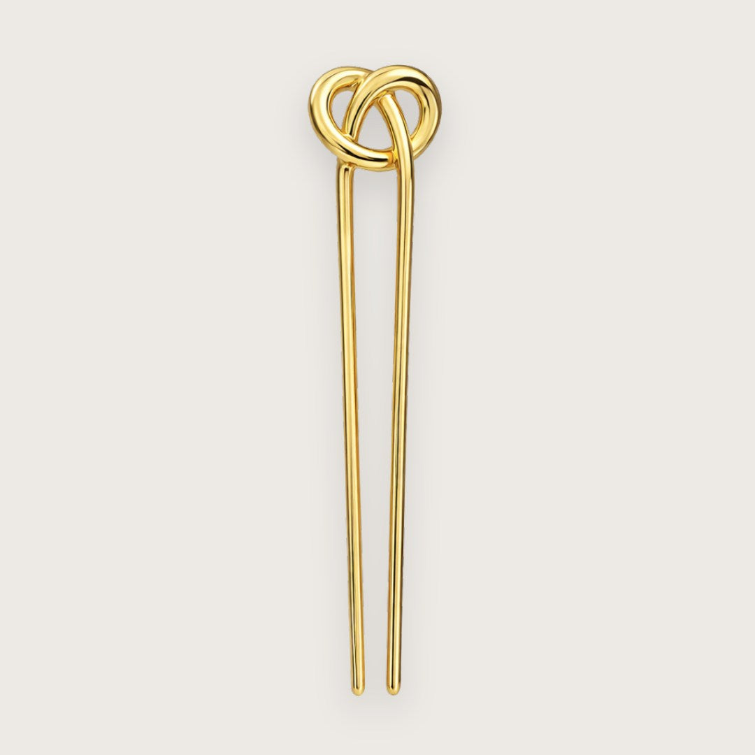 Cady er en elegant fransk hårnål med et skulpturelt og enkelt udtryk, hvor den dekorative knude i toppen giver et diskret, men iøjnefaldende twist. Den glatte, guldfarvede overflade reflekterer lyset smukt og tilfører et eksklusivt præg, uanset om håret er sat op eller bæres mere løst og afslappet.

Hårnålen er fremstillet i guldfarvet metal og måler ca. 12,3 cm i længden og ca. 3 cm i bredden ved toppen, og med en vægt på ca. 27 g føles den solid og behagelig i håret. fransk hårnål guld
