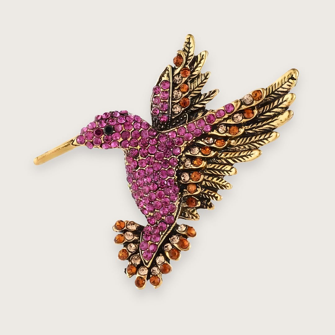 Guldfarvet kolibri-broche med farvede rhinsten i Y2K-stil.

Emi-brochen er en klassiker for Millennials, men som smykke kan den næppe kaldes klassisk.

Med farvede rhinsten i pink, orange og gul og form som en kolibri, er designet mere 00'er end evergreen, men 00'erne er afgjort tilbage, med alt hvad det indebærer af similisten og dyremotiver.&nbsp;

Emi-brochen er til de af jer, der elsker viben, men (heller) ikke har lyst til at gå all in og tatovere (endnu) en delfin på anklen.

Lille kolibri-broche 