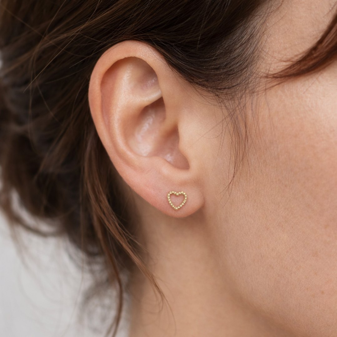 Disse fine hjerteørestikkere er designet som små, elegante studs med et enkelt og stilrent hjertemotiv.

Det lille hjerte giver øreringene et diskret symbolsk udtryk, samtidig med at designet forbliver let og minimalistisk. Resultatet er et par små øreringe, der fungerer både til hverdag og til konfirmationer.

Smykker til konfirmation, studenterfest, bryllup, hverdag.

Ørestikkerne er fremstillet i rustfrit stål med 18k PVD-forgyldning. vandfaste øreringe.

konfirmationsøreringe, konfirmation ørestikkere.