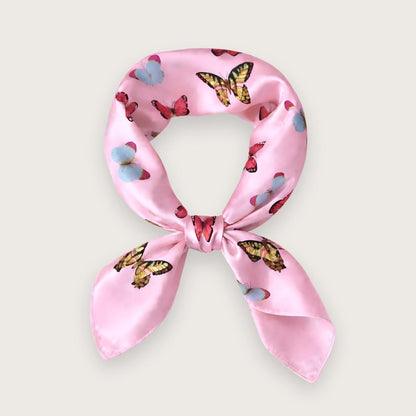 Lyserødt satintørklæde med sommerfugle i pink, blå og lilla nuancer. Y2K-inspireret satin scarf i silkeblanding med glossy finish og farverigt butterfly print. Trendy hårtørklæde og halstørklæde til kvinder, stylet med Scandinavian cool girl og Pinterest fashion vibe. Pink satintørklæde til styling om halsen, i håret eller på tasken. 60x60 cm satin tørklæde med 30% silke og 70% polyester.
Satin tørklæde med sommerfugle i 00'er-stil. Trendy satintørklæde. Lyserødt silketørklæde til halsen.