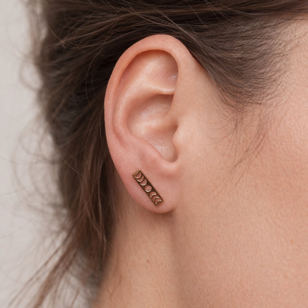 Smukke ørestikkere i 18k forgyldt stål.

De elegante Luna stav-ørestikkere med månefaser kombinerer et stilrent, geometrisk design med et dekorativt himmelmotiv. Den slanke, rektangulære form giver øreringene et moderne udtryk, mens de udskårne månefaser tilfører en fin detalje, der fanger lyset og giver smykket karakter.

Designet fungerer både minimalistisk og symbolsk. Månefasemotivet har længe været forbundet med naturens rytme og forandring. Månesmykker. Måneøreringe.