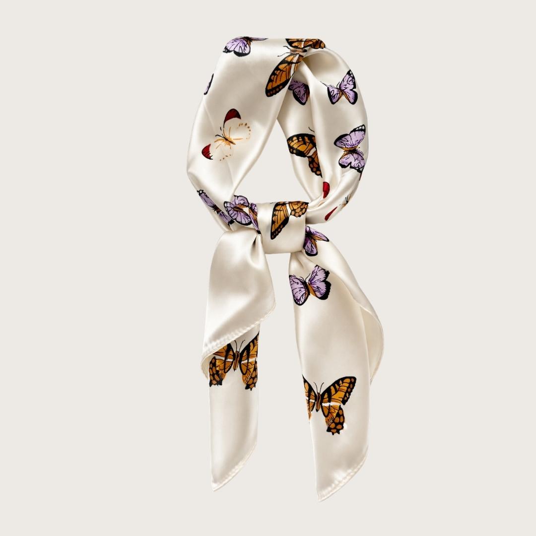 Hvidt satintørklæde med sommerfugle i smukke farver. Y2K-inspireret satin scarf i silkeblanding med glossy finish og farverigt butterfly print. Trendy hårtørklæde og halstørklæde til kvinder, stylet med Scandinavian cool girl og Pinterest fashion vibe. Pink satintørklæde til styling om halsen, i håret eller på tasken. 60x60 cm satin tørklæde med 30% silke og 70% polyester.
Satin tørklæde med sommerfugle i 00'er-stil. Trendy satintørklæde. Cremefarvet silketørklæde til halsen.
